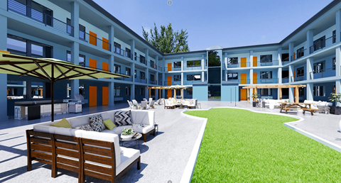 a grassy courtyard with a couch and chairs in front of a building
