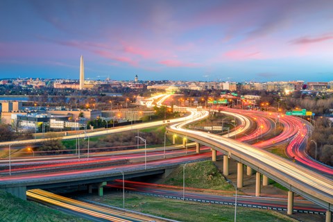 A highway with multiple lanes of traffic leading towards the Washington Monument.