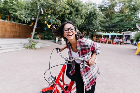 A woman is riding a red bicycle in a park.