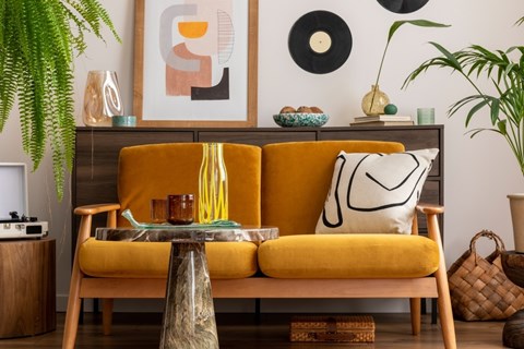 A living room with a yellow couch and a wooden table.
