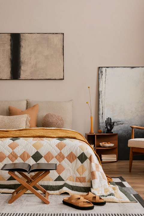 A bedroom with a bed, chair, and a painting on the wall.