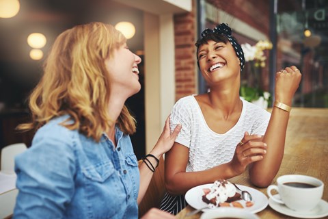 Two women enjoying a dessert and coffee in a cafe.