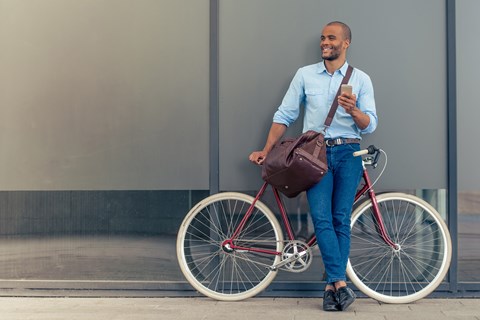 A man is standing next to a bicycle holding a phone.