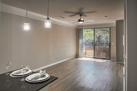 Open-concept living and dining area with wood-look flooring, ceiling fan, and sliding glass door in a one-bedroom apartment home