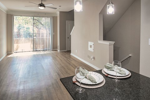View from the breakfast bar into the open living area with large window and wood-look flooring at The Brownstones in Far North Dallas