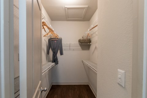 This is a photo of the bedroom walk-in closet of the 826 square foot 1 bedroom apartment at The Brownstones Townhome Apartments in Dallas, TX.