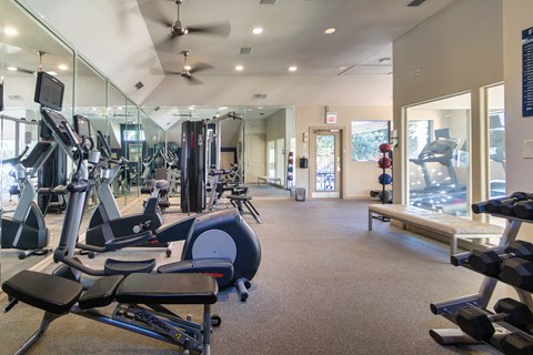 The 24-hour fitness center with treadmills, elliptical machines, and free weights at The Brownstones Townhome Apartments in the Far North Dallas neighborhood of Dallas, TX..