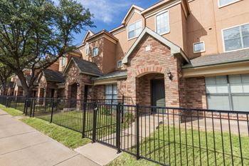 This is a photo of the townhome exteriors with a gated front yard at The Brownstones Townhome Apartments in Dallas, TX.