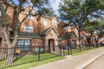 This is a photo of the townhome exteriors with a gated front yard at The Brownstones Townhome Apartments in Dallas, TX.