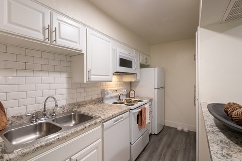 A kitchen with white cabinets and a white fridge.