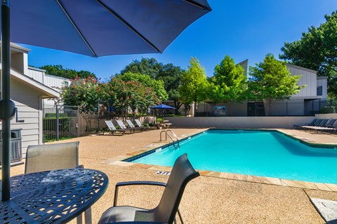 A pool surrounded by chairs and trees at The Biltmore Apartments located in the Vickery Midtown neighborhood of Dallas, TX.