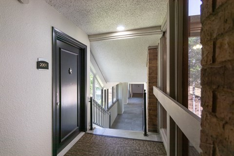 the hallway of a house with a door open to a hall way and a staircase