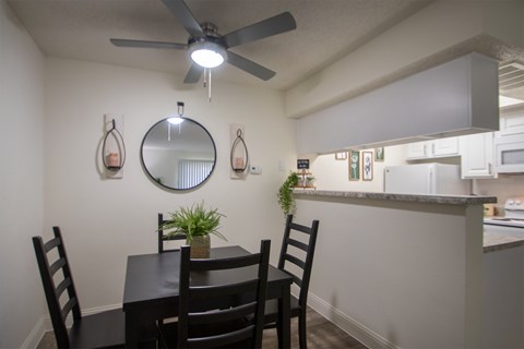 A dining room with a table and chairs in a 515 square foot 1 bedroom, 1 bath apartment home at Canyon Creek Apartments in Dallas Midtown neighborhood of Dallas, TX.