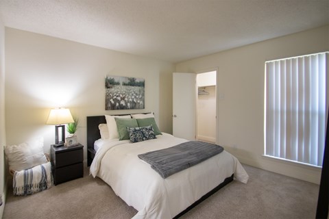 A bedroom with a large bed and a painting on the wall.