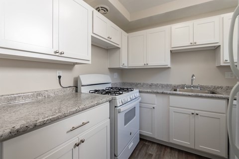 a white kitchen with granite counter tops and white cabinets