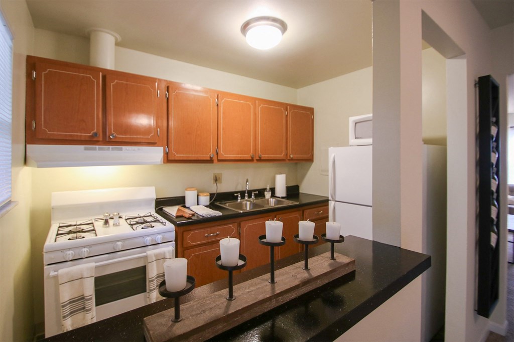 This is a photo of the kitchen with pass through breakfast bar of the 550 square foot 1 bedroom, 1 bath, balcony floor plan model apartment at College Woods Apartments in Cincinnati, OH.