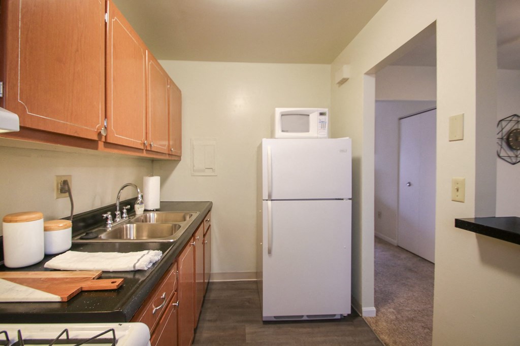 This is a photo of the kitchen with pass through breakfast bar of the 550 square foot 1 bedroom, 1 bath, balcony floor plan model apartment at College Woods Apartments in Cincinnati, OH.