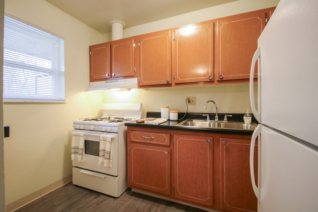 This is a photo of the kitchen with pass through breakfast bar of the 550 square foot 1 bedroom, 1 bath, balcony floor plan model apartment at College Woods Apartments in Cincinnati, OH.