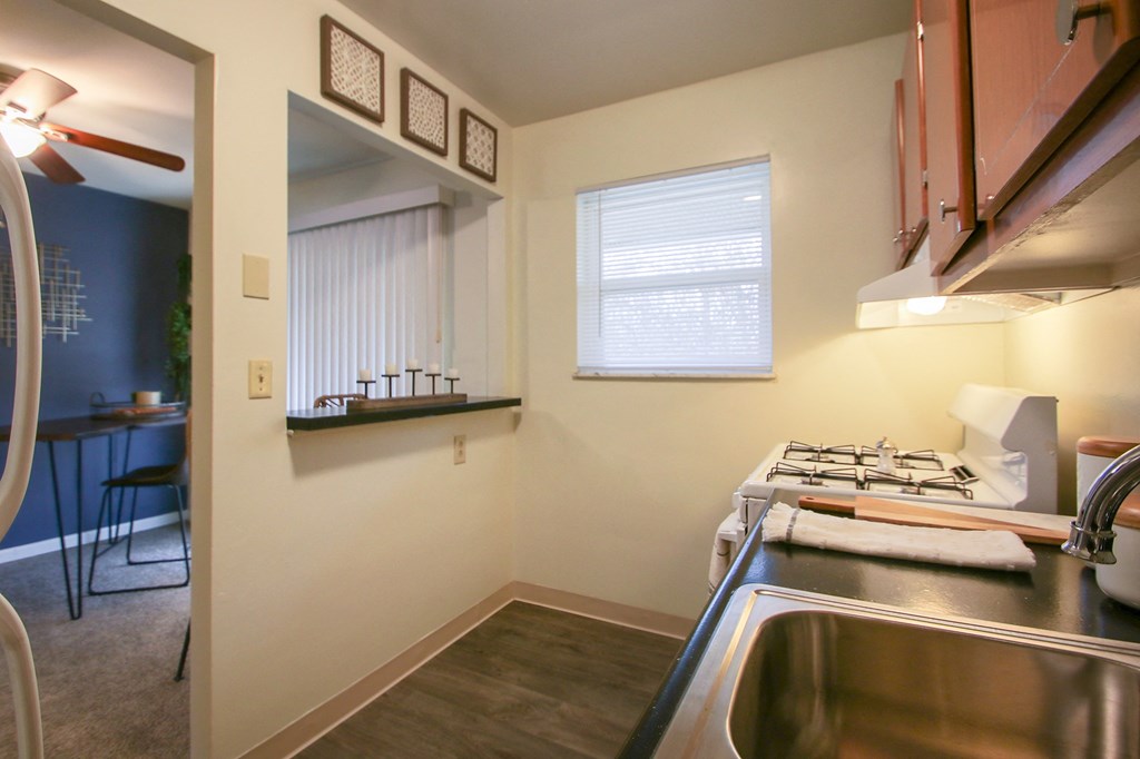 This is a photo of the kitchen with pass through breakfast bar of the 550 square foot 1 bedroom, 1 bath, balcony floor plan model apartment at College Woods Apartments in Cincinnati, OH.