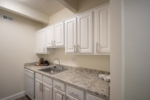 A kitchen with white cabinets and granite countertops.
