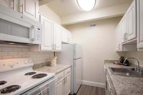 A kitchen with a white stove, microwave, and refrigerator.