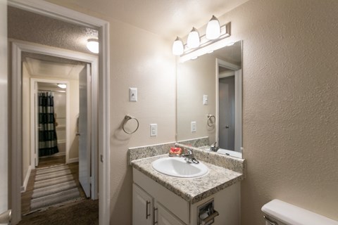 a bathroom with a sink and a mirror and a hallway to a bedroom