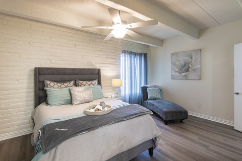 Bedroom with ceiling fan, wide window, and wood-look flooring in a one-bedroom apartment home at Harvard Square Apartments