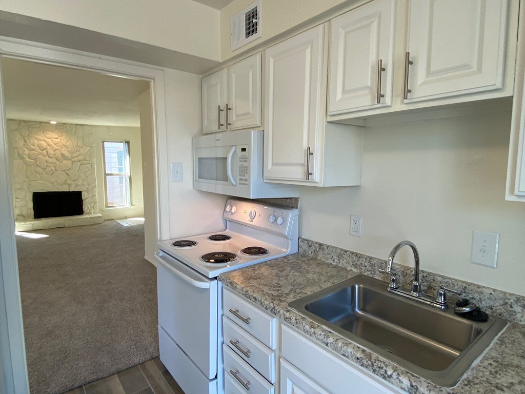 a kitchen with white cabinets and a sink and a stove