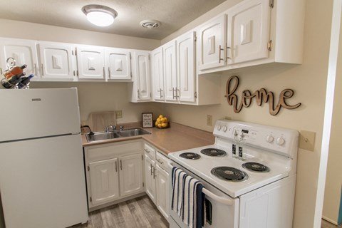 a kitchen with white cabinets and appliances and a stove and refrigerator