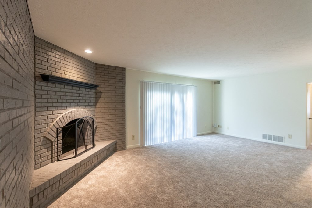 This is a photo the living room with brick wall and wood-burning fireplace of the 925 square foot, Hazelnut 2 bedroom, 1 bath apartment at Montana Valley Apartments in the Westwood neighborhood of Cincinnati, OH.
