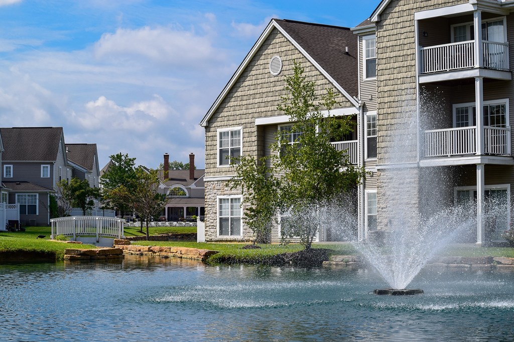 This is a picture of a pond with a fountain and  building exteriors at Nantucket Apartments, in Loveland, OH.