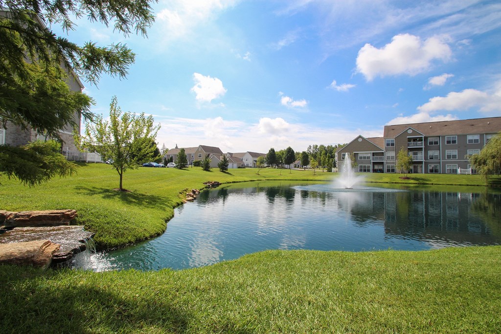 This is a picture of a pond with a fountain and  building exteriors at Nantucket Apartments, in Loveland, OH.