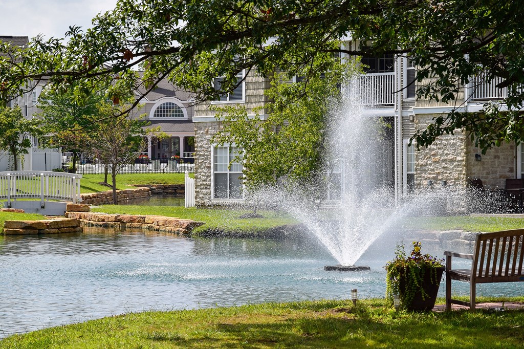 This is a picture of a pond with a fountain and  building exteriors at Nantucket Apartments, in Loveland, OH.