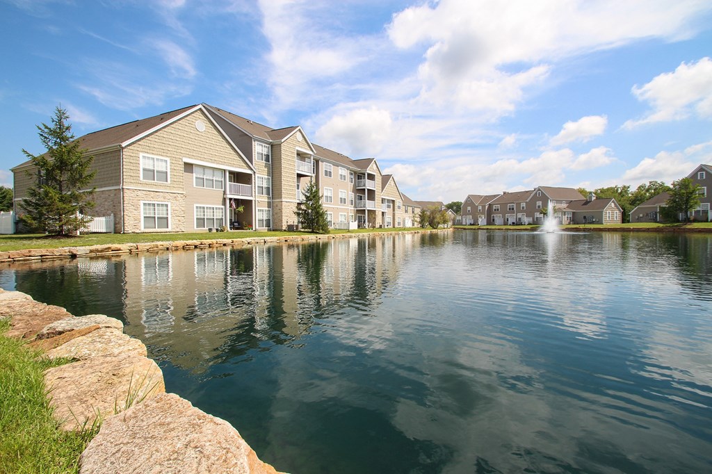 This is a picture of a pond with a fountain and  building exteriors at Nantucket Apartments, in Loveland, OH.