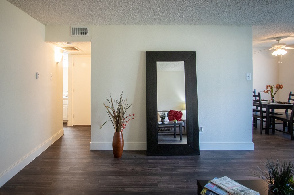 an empty living room with a mirror in the middle of it