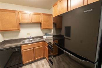 This is a photo of a kitchen with honey oak cabinets and black appliances in a 560 square foot 1, 1 bath apartment at Park Lane Apartments in Cincinnati, OH.