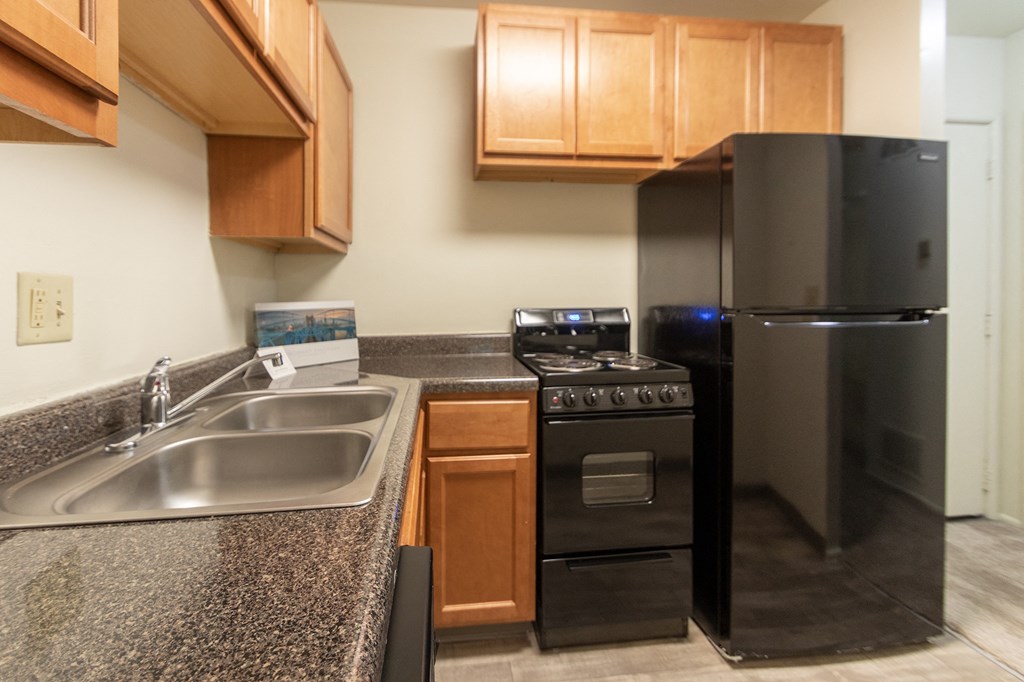 This is a photo of a kitchen with honey oak cabinets and black appliances in a 560 square foot 1, 1 bath apartment at Park Lane Apartments in Cincinnati, OH.