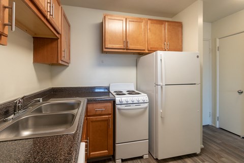 This is a photo of a kitchen with honey oak cabinets and white appliances in a 560 square foot 1, 1 bath apartment at Park Lane Apartments in Cincinnati, OH.