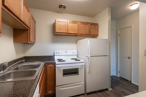 This is a photo of a kitchen with honey oak cabinets and white appliances in a 560 square foot 1, 1 bath apartment at Park Lane Apartments in Cincinnati, OH.