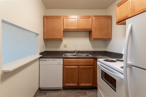 This is a photo of a kitchen with honey oak cabinets and white appliances in a 560 square foot 1, 1 bath apartment at Park Lane Apartments in Cincinnati, OH.