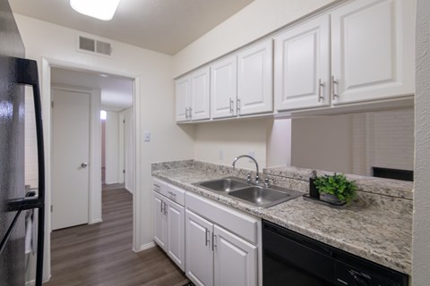 A kitchen with white cabinets and a granite countertop.
