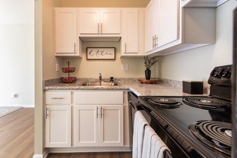 A kitchen with white cabinets and a black stove top.