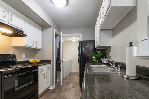 a kitchen with black appliances and white cabinets and a stainless steel sink