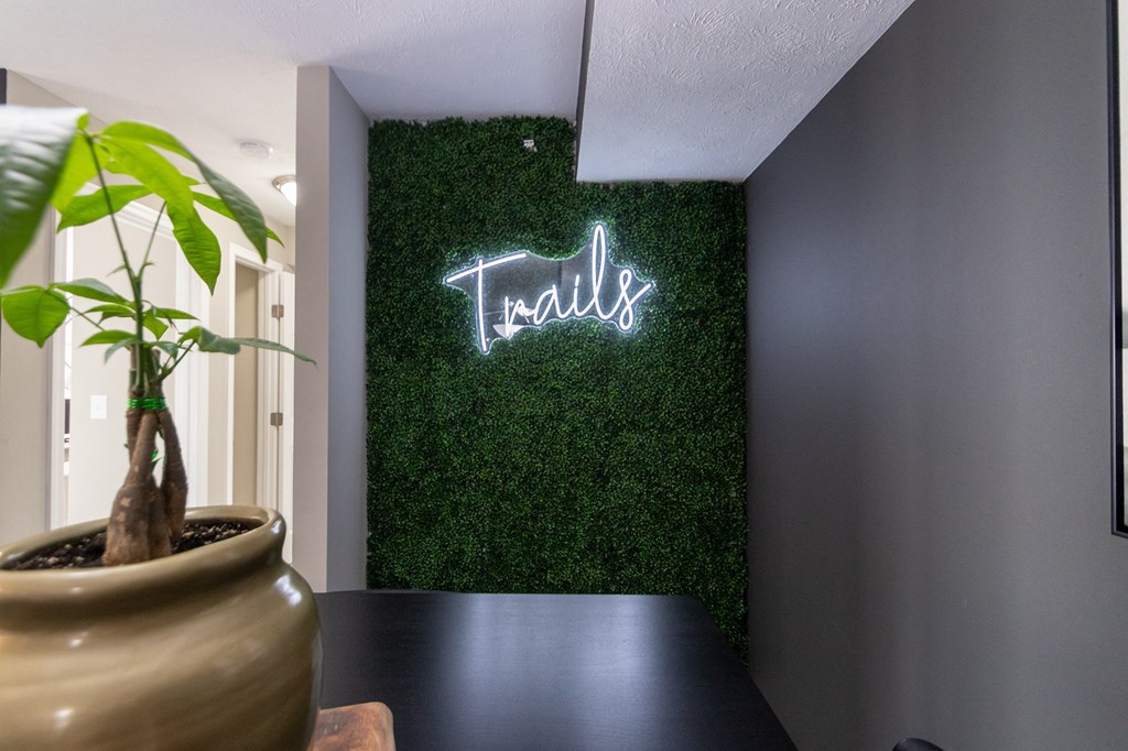 This is a photo of a green wall with a neon sign that says trails in the dining room in the 1226 square foot 3 bedroom, 2 bath Hambletonian at Trails of Saddlebrook Apartments in Florence, KY.