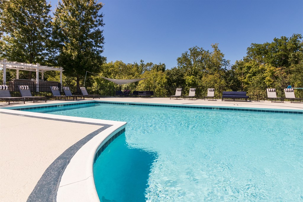 a swimming pool with chairs and trees in the background