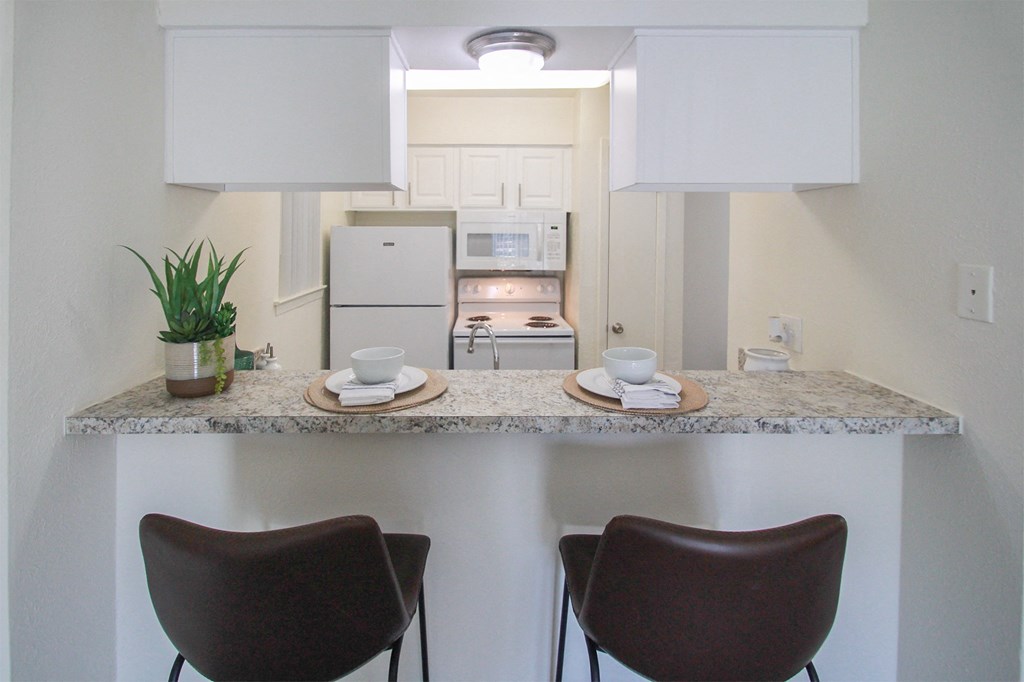 This is a photo of the breakfast bar and kitchen in the 558 square foot 1 bedroom, 1 bath model apartment at The Summit at Midtown Apartments in Dallas, TX.
