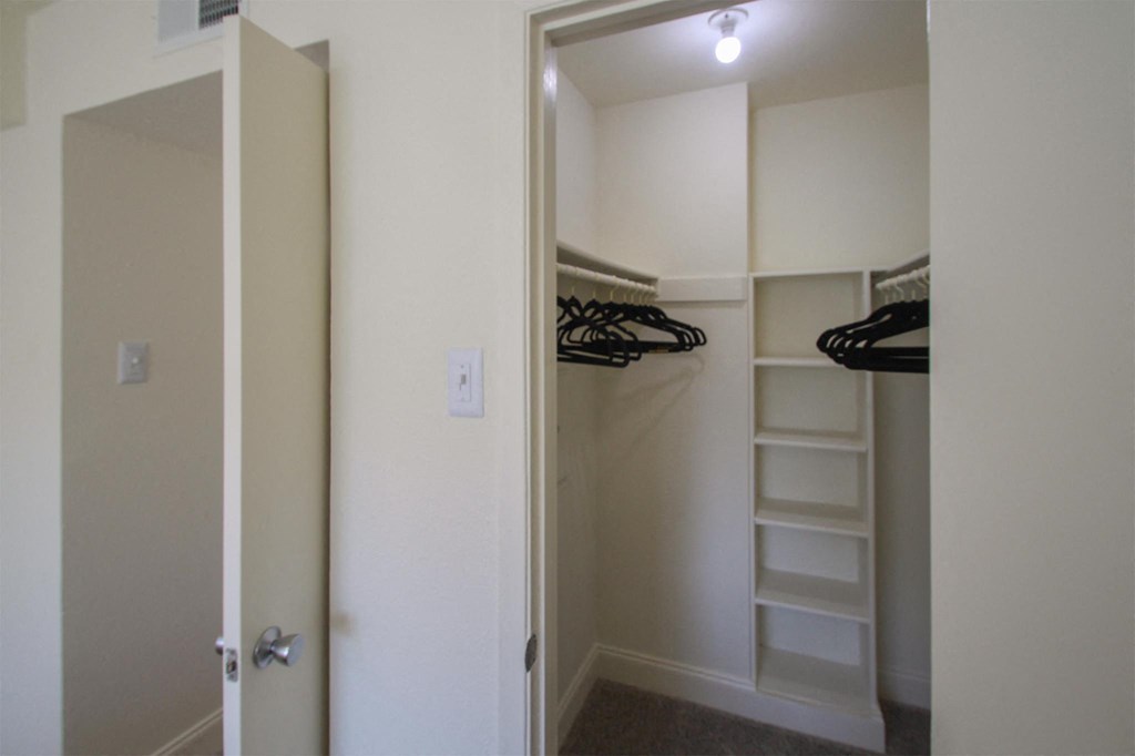 This is a photo of the bedroom walk-in closet in the 558 square foot 1 bedroom, 1 bath model apartment at The Summit at Midtown Apartments in Dallas, TX.