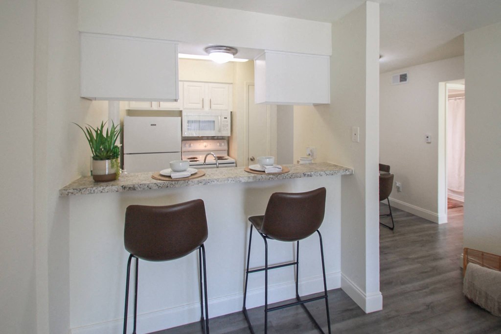 This is a photo of the breakfast bar and kitchen in the 558 square foot 1 bedroom, 1 bath model apartment at The Summit at Midtown Apartments in Dallas, TX.