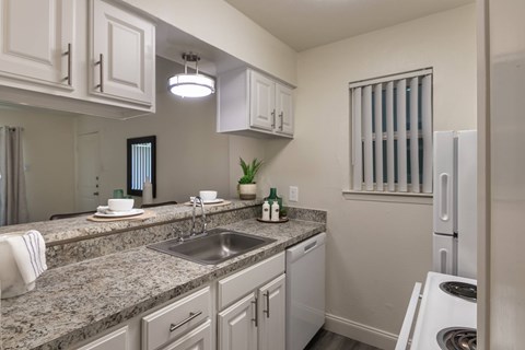 A kitchen with granite countertops and white cabinets.