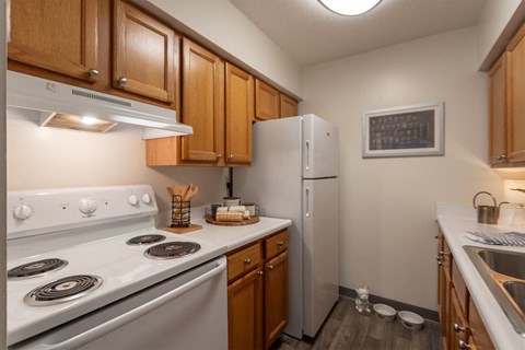 a kitchen with white appliances and wooden cabinets and a refrigerator